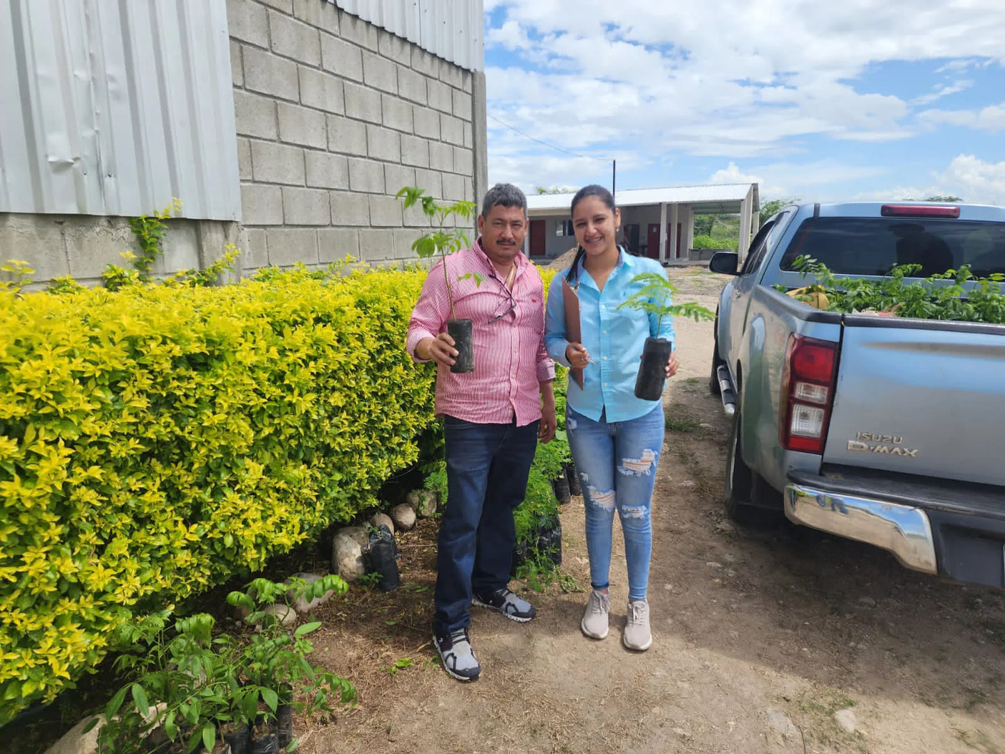 Honduran coffee producer Elvin Suazo and a family member holding young coffee seedlings outside the farm nursery.