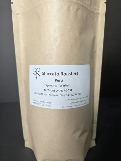Fresh roasted Staccato Roasters Peru Cajamarca medium dark roast whole bean coffee in a 12 oz kraft coffee bag.